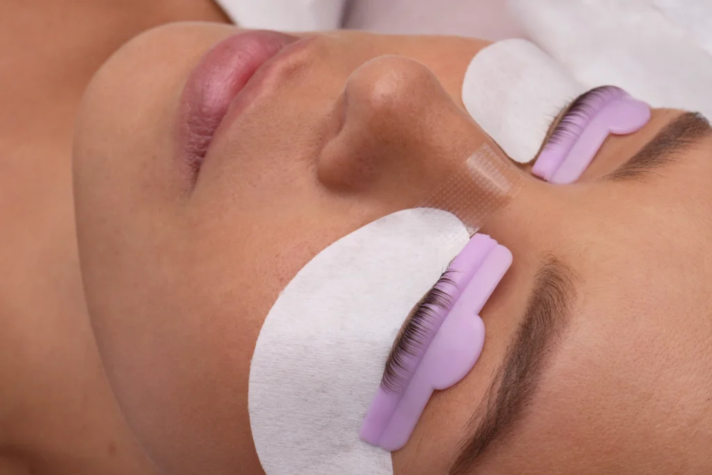 The image shows a client resting with her eyes closed during a lash treatment.