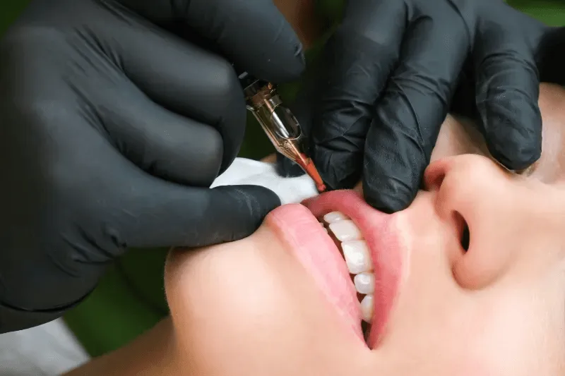 A practitioner applies soothing techniques to ensure comfort and manage pain during a lip blush procedure.