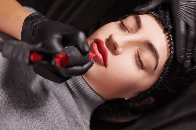 The image showcases a close-up of a person receiving a permanent lip tint procedure.